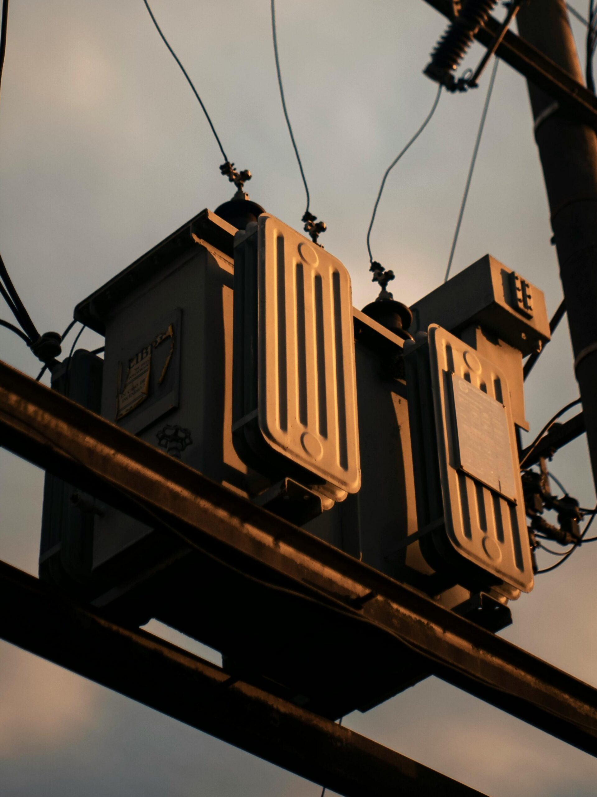 A dramatic shot of a transmission tower with power lines silhouetted against a sunset sky.